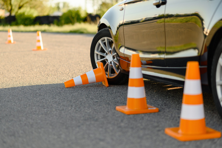 Car and downed traffic cone, lesson in driving school concept, nobody. Teaching to drive vehicle theme. Driver's license education